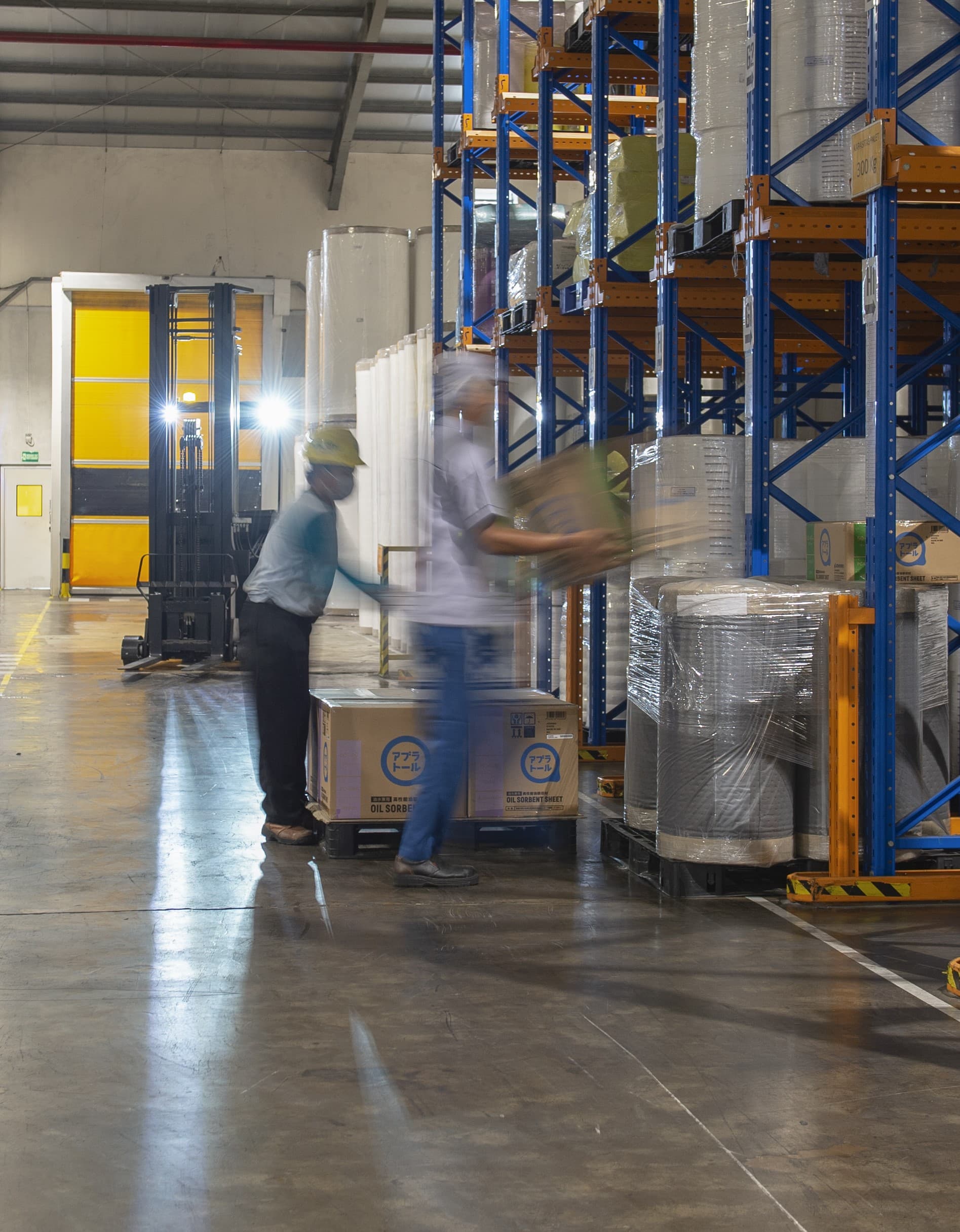 Large warehouse facility with tall racks stacked with white rolls of nonwoven materials