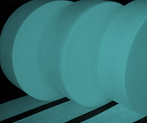 Large rolls of cyan-colored nonwoven fabric in a manufacturing facility