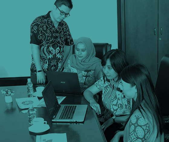Team of four professionals collaborating around a laptop in a meeting room
