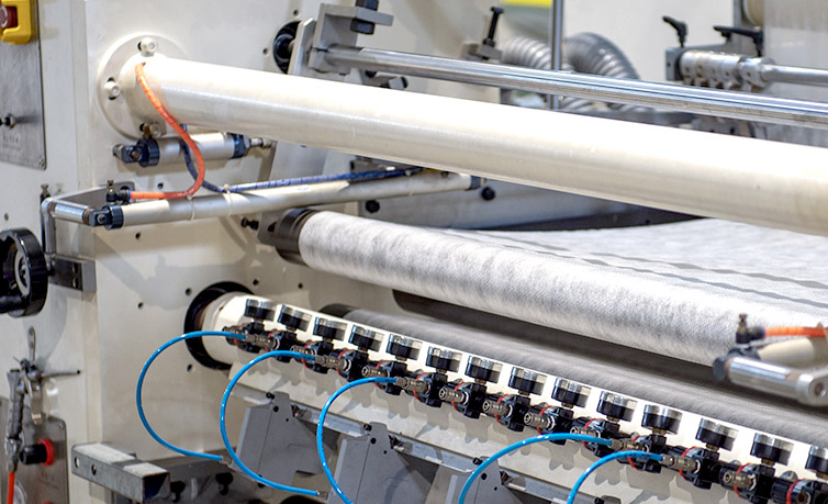 Detailed view of industrial machinery processing white nonwoven fabric