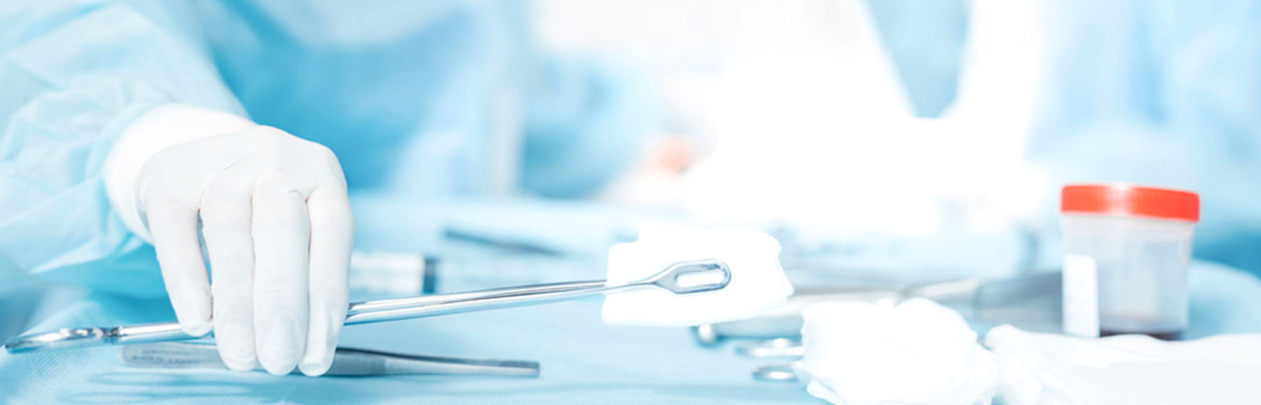 Gloved hand reaching for surgical instruments on a sterile tray