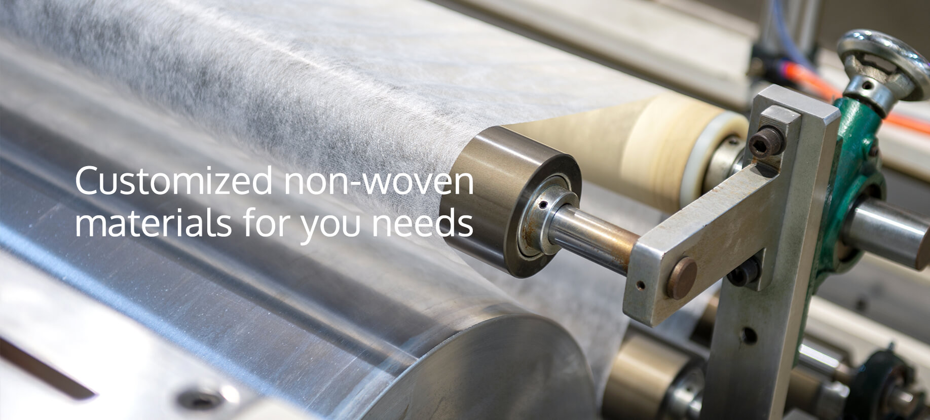 Close-up of a manufacturing machine processing white nonwoven fabric materials