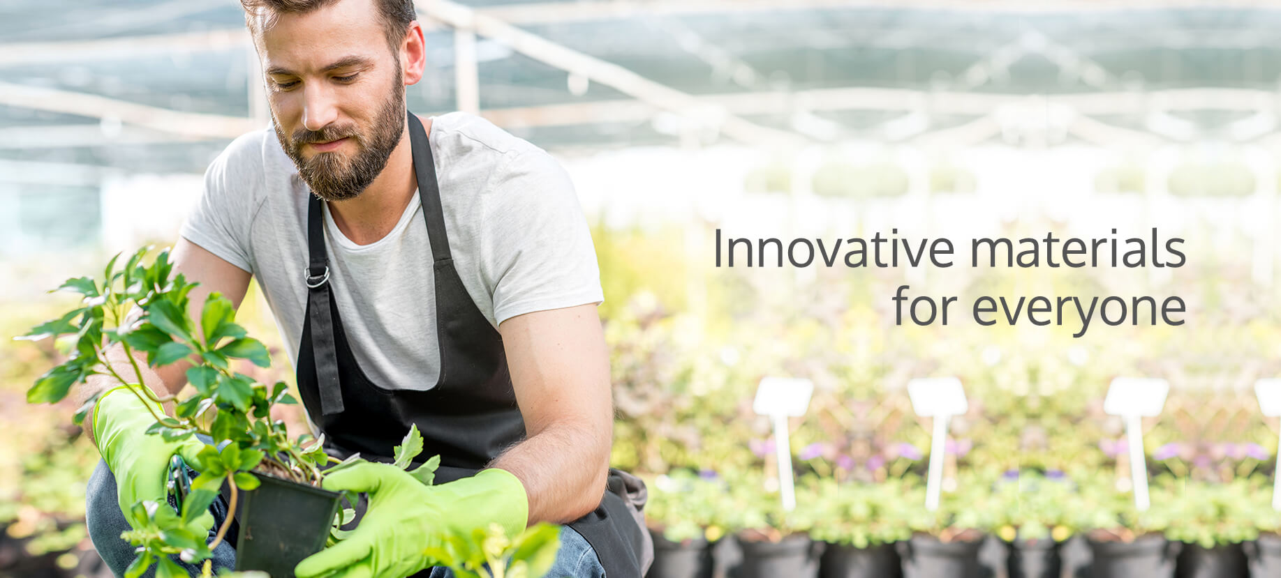 A male gardener in a greenhouse tending to small potted plants