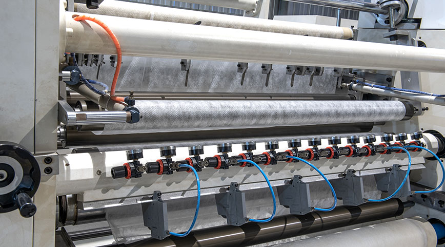 Detailed view of a machine with multiple blue pneumatic hoses and pressure gauges processing material