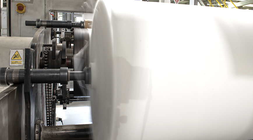 High-speed spinning roll of white fabric on an industrial manufacturing line