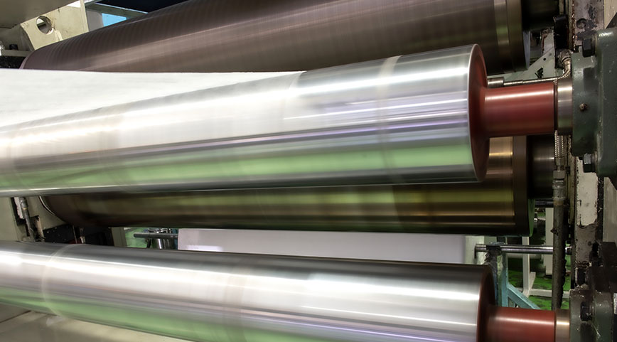 Close-up of three large metallic rollers in an industrial machine